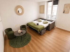 A modern bedroom with a bed, two chairs, a round table, and a window with a view. - Charmant Studio Paris 11 - faubourg du temple (Paris)