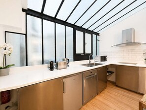 Eine moderne Küche mit großem Fenster, Edelstahlgeräten und einer weißen Arbeitsplatte.