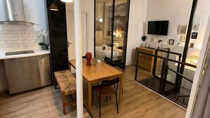 A modern kitchen with a dining area, a TV, and a large window. - Duplex Design Montparnasse - Baby-foot - 6P (Paris)