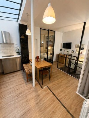 Eine moderne Küche mit Essbereich, einem Fernseher und einem großen Fenster.