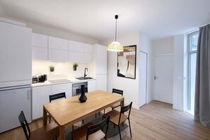 Eine moderne Küche mit weißen Schränken, einem Holztisch und einer Pendelleuchte.