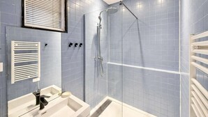 A bathroom with a shower, a sink, and a towel rack. - Appartement Élégant -  Montparnasse - 6 Personnes (Paris)