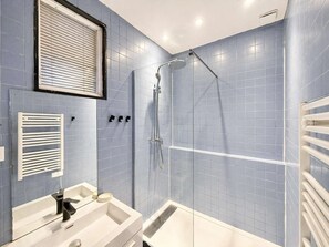 A bathroom with a shower, a sink, and a towel rack.