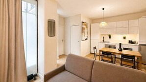A modern apartment with a living room, dining area, and kitchenette. - Appartement Élégant -  Montparnasse - 6 Personnes (Paris)