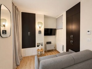 Ein modernes Schlafzimmer mit Sofa, Fernseher, Kleiderschrank und Heizkörper.