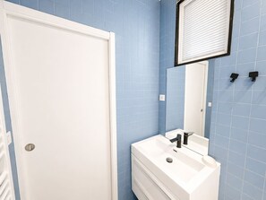 Ein Badezimmer mit einem weißen Waschbecken, einem Spiegel und blauen Fliesenwänden.