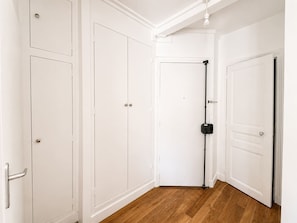 Ein Flur mit weißen Türen, einer schwarzen Überwachungskamera und Holzdielen.