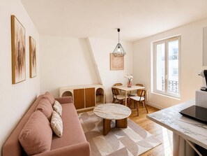 Ein modernes Wohnzimmer mit Sofa, Esstisch mit Stühlen, einer Pendelleuchte und Blick ins Freie.
