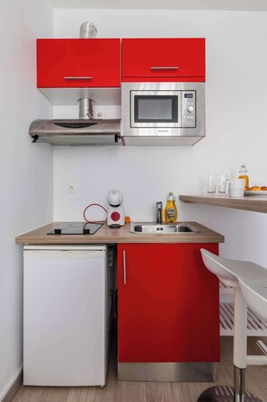 Eine kleine Küche mit Mikrowelle, kleinem Kühlschrank und Spüle.
