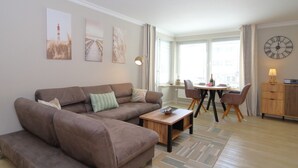 Ein Wohnzimmer mit einem braunen Sofa, einem Holztisch und einem Essbereich mit einem runden Tisch und Stühlen.
