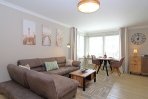 Ein Wohnzimmer mit einem braunen Sofa, einem Holztisch und einem Essbereich mit einem runden Tisch und Stühlen.