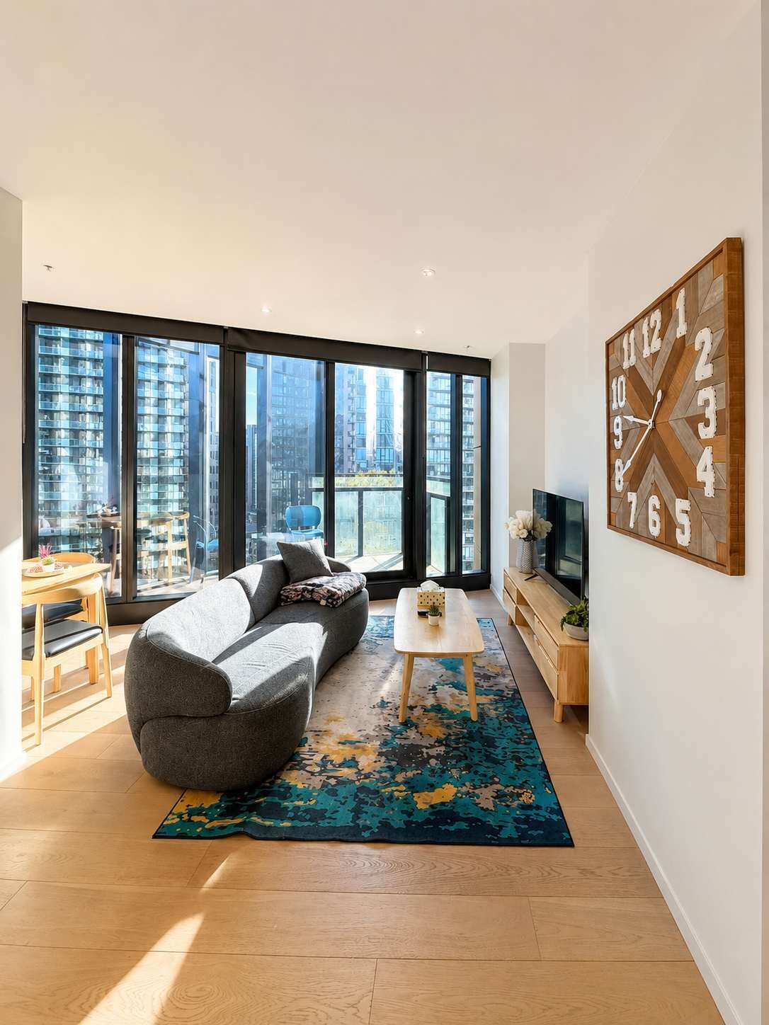 A modern living room with a sofa, coffee table, and a large wall clock.