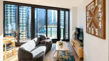 A modern living room with a sofa, coffee table, and a large wall clock.