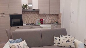 Eine moderne Küche mit Einbauofen, einem Essbereich mit einer Couch und einer weißen Tür.