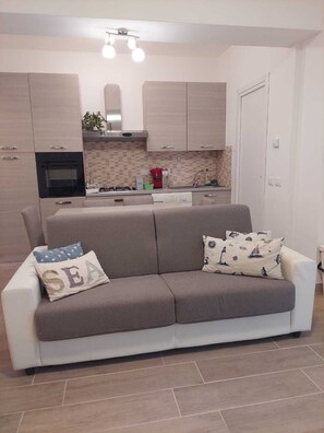 Eine moderne Küche mit Einbauofen, einem Essbereich mit einer Couch und einer weißen Tür.