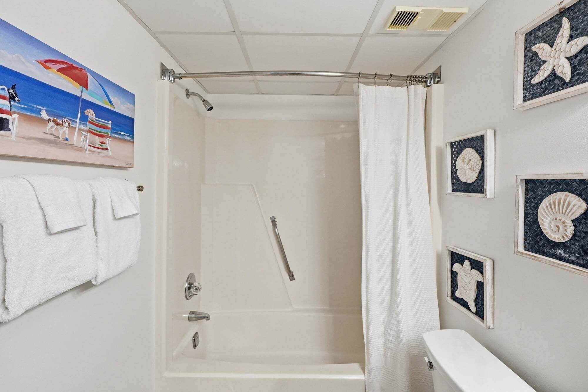 A bathroom with a shower, a towel rack, and decorative wall art.