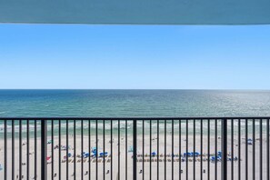 A beach view from a balcony with a railing, clear sky, and ocean. - Watercrest 1404 - Free Beach Chairs! (Panama City)