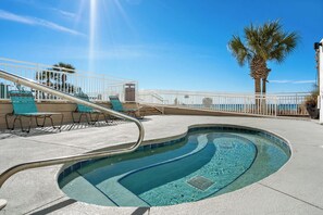 A swimming pool with a curved design, a white railing, and a palm tree in the background. - Watercrest 1404 - Free Beach Chairs! (Panama City)