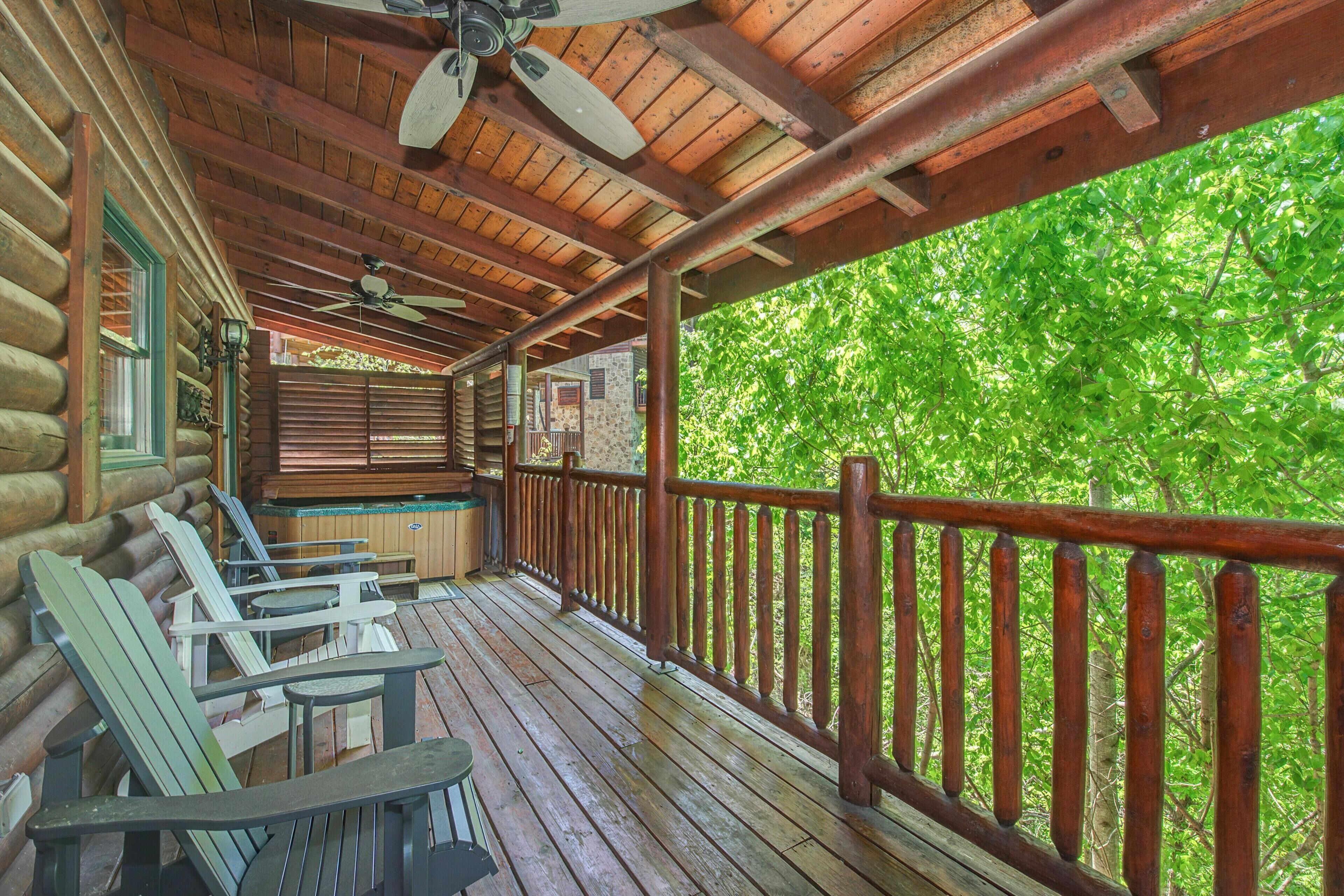 A wooden deck with Adirondack chairs, a table, and a ceiling fan.