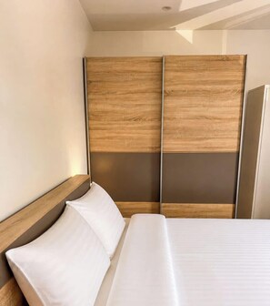 Camera d'albergo con un letto, una testiera in legno e un grande specchio.
