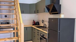 Eine Küche mit eingebautem Herd, einem Kühlschrank und einer Holztreppe.