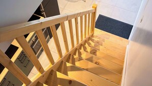 Eine Holztreppe führt zu einem Essbereich mit einem runden Tisch und Stühlen.