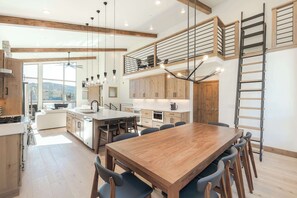 A modern kitchen with wooden cabinets, a large island, and a dining area with a wooden table and chairs. - First Tracks. Luxury Ski Estate & Rooftop Sauna (Winter Park)
