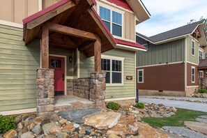A residential building with a stone porch, a red door, and a garage. - Mountain High (Gatlinburg)