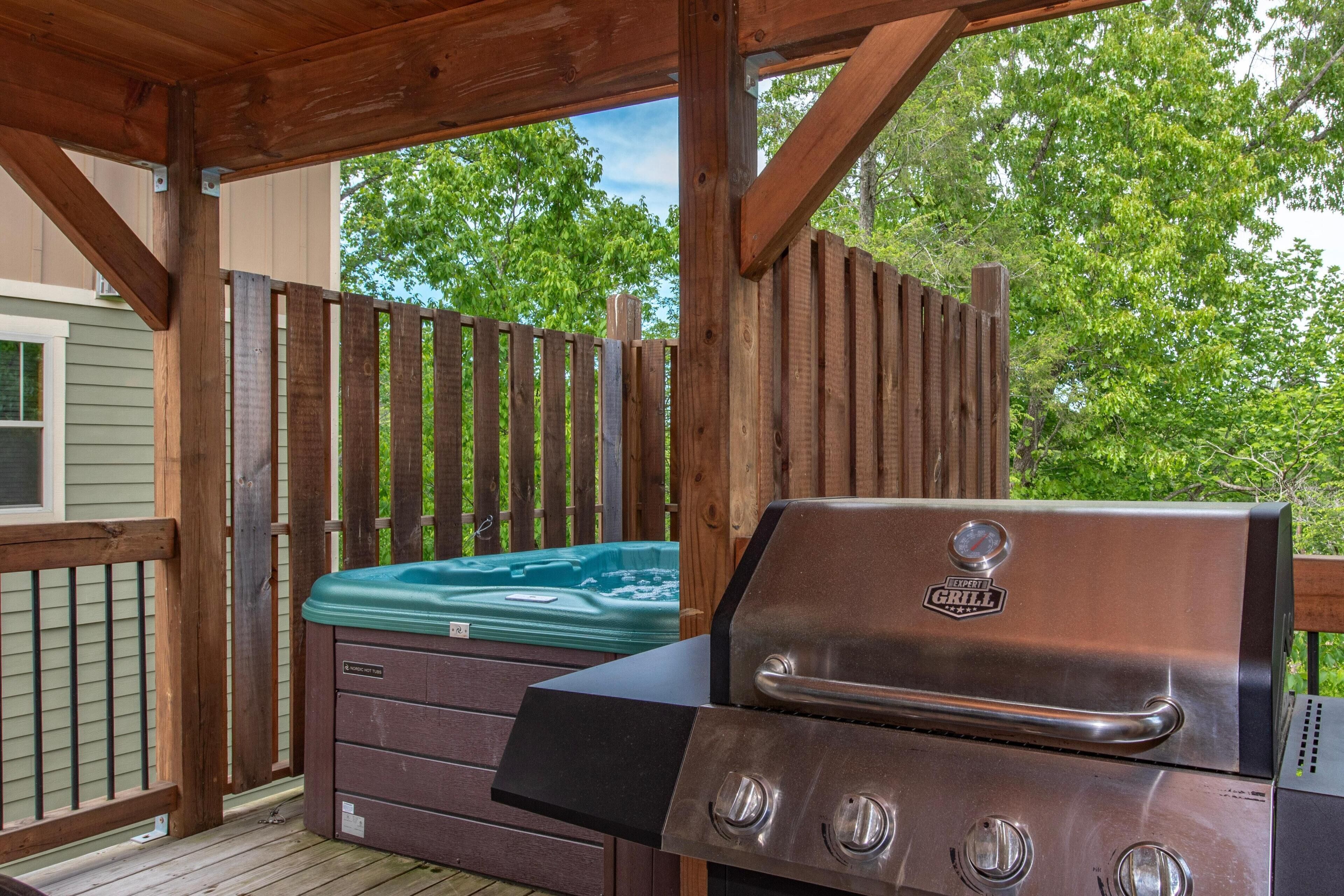 Eine Terrasse mit Whirlpool, Grill und Holzzaun.