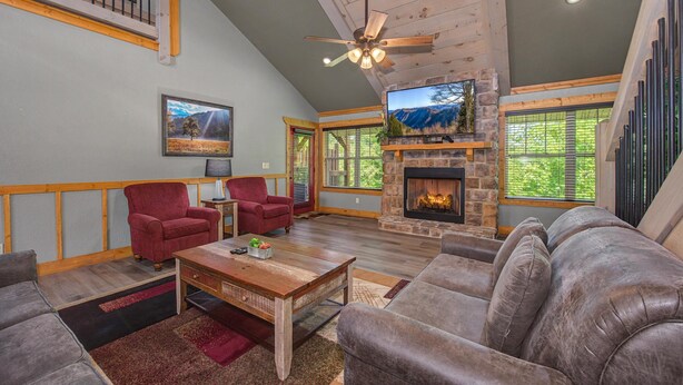 A spacious living room with a fireplace, comfortable seating, and a television. - Mountain High (Gatlinburg)