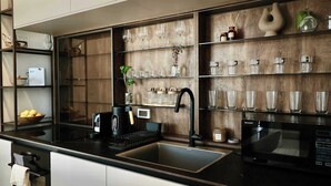 Cozinha moderna com bancada preta, pia embutida, cafeteira e micro-ondas.
