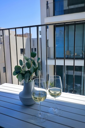 Ein Balkon mit einem Blumentopf und zwei Gläsern Weißwein.