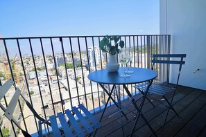 A balcony with a table and chairs, a potted plant, and a glass of wine. - High-End 1BR in Secure Tower | Parking | Mamak (Tel Aviv-Yafo)