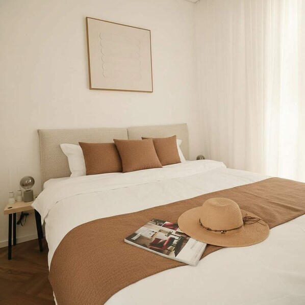 A hotel room with a bed, a magazine, a hat, and a framed picture on the wall.