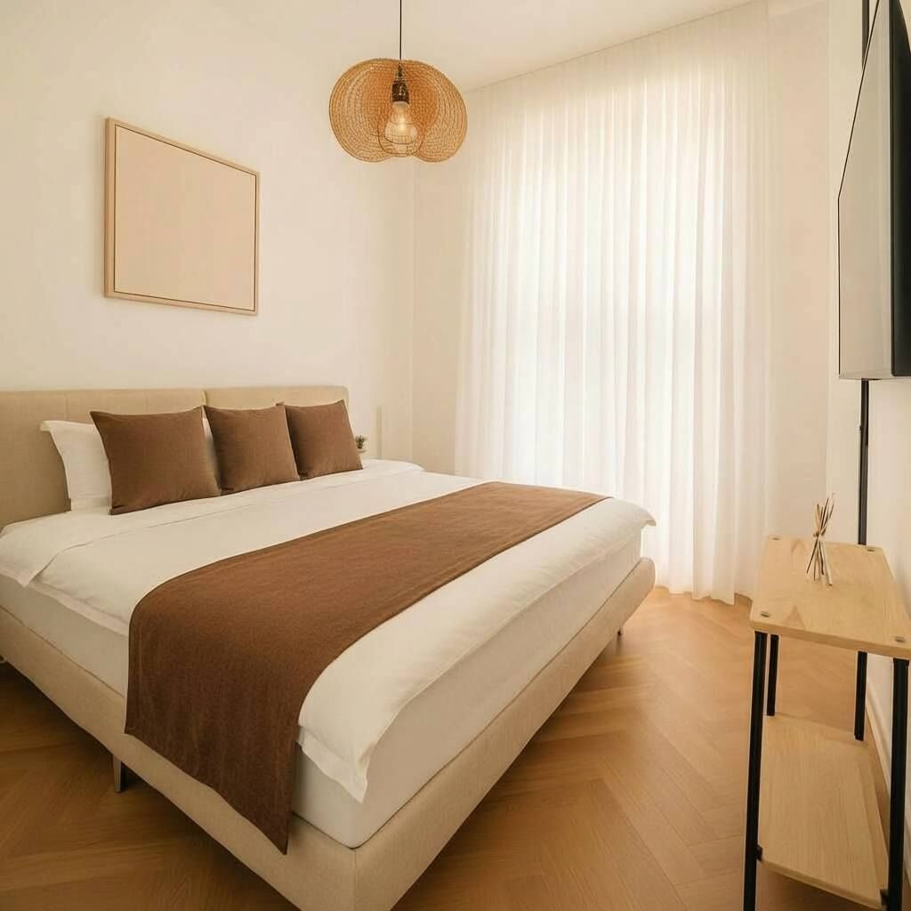 Un dormitorio con cama, mesita de noche, lámpara colgante y televisión instalada en la pared.
