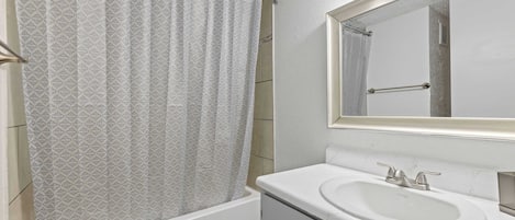 A bathroom with a bathtub, a sink, and a mirror.