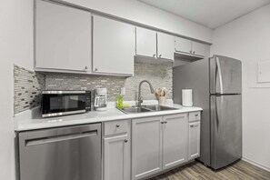 A modern kitchen with stainless steel appliances, white cabinets, and a tiled backsplash. - AT&T Stadium Getaway | Parking (Arlington)
