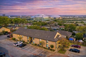 A building with a flat roof and a parking lot in front. - AT&T Stadium Getaway | Parking (Arlington)