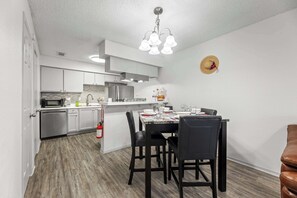 A modern kitchen with white cabinets, a built-in microwave, and a stainless steel range hood. - AT&T Stadium Getaway | Parking (Arlington)