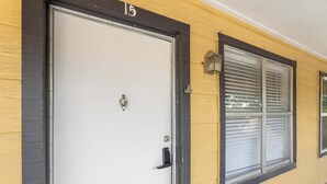 A building with a white door, a window with blinds, and a number '15' above the door. - City Comfort • 2BR • Stadium Within Walking (Arlington)