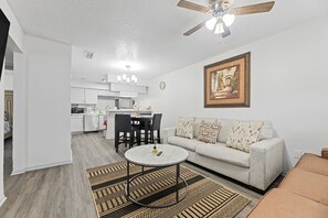 Ein Wohnzimmer mit einer Couch, einem Couchtisch und einem Essbereich mit Stühlen und Tisch.