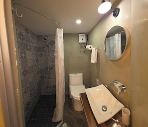 A bathroom with a shower, toilet, sink, and a mirror.