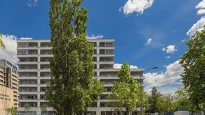 A multi-story residential building with a central courtyard, surrounded by trees and a clear sky. - Comfortable Studio with a Balcony | Near Westfield Mokotów (Warszawa)