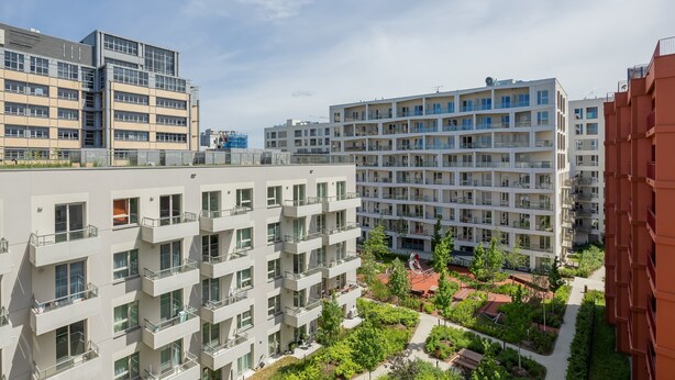 A multi-story residential building with balconies, a courtyard with greenery, and a clear sky. - Comfortable Studio with a Balcony | Near Westfield Mokotów (Warszawa)