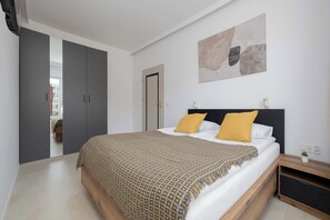 Ein Schlafzimmer mit Bett, Kleiderschrank, Nachttisch und Wandbild.