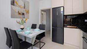 A modern kitchen with a black refrigerator, a dining table with chairs, and a vase with flowers. - Comfortable Studio with a Balcony | Near Westfield Mokotów (Warszawa)