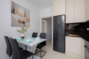 Eine moderne Küche mit einem schwarzen Kühlschrank, einem Esstisch mit Stühlen und einer Vase mit Blumen.