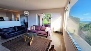 Ein modernes Wohnzimmer mit Sofa, Couchtisch und Blick ins Freie.