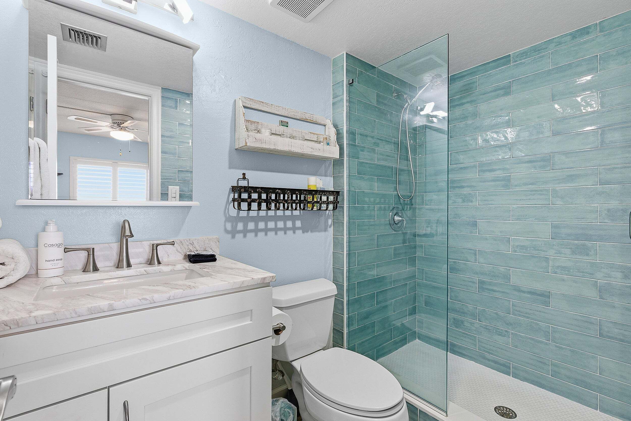 Une salle de bain avec une douche à parois de verre, des toilettes blanches et un lavabo en marbre.