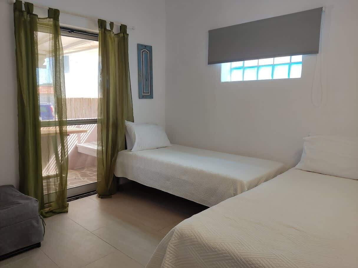 A room with two beds, a window with a view, a curtain, and a small table.